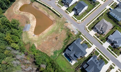 Aerial view of residential neighborhood with retention pond and newly built homes