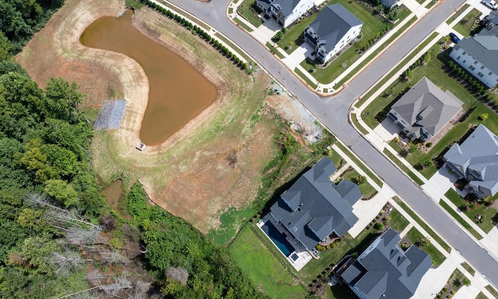 Aerial view of residential neighborhood with retention pond and newly built homes