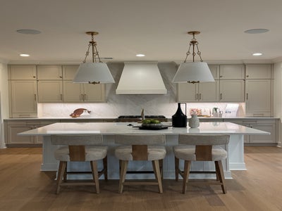 Modern kitchen with beige cabinets, white island, pendant lights, and four bar stools