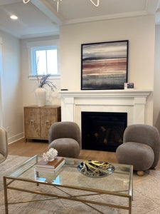 Living room with white fireplace mantel, gray upholstered chairs, and glass coffee table