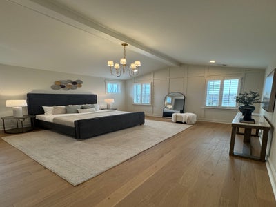 Master bedroom with vaulted ceiling, black bed frame, chandelier, and hardwood floors