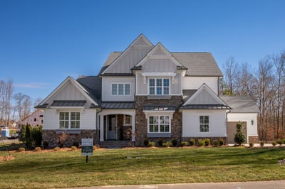 Two-story home with white siding, stone accents, and multiple gabled rooflines
