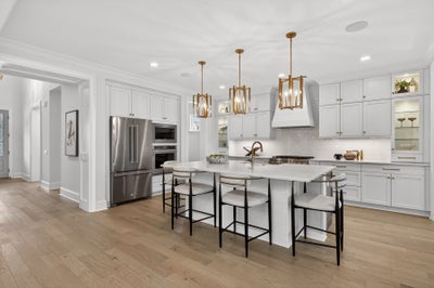 Modern white kitchen with large island, stainless appliances, and gold pendant lights