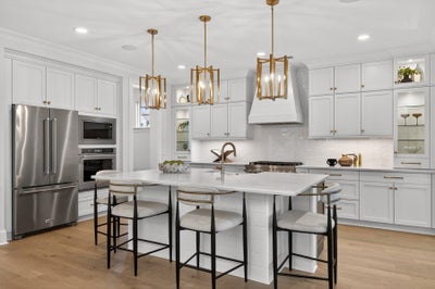 White kitchen with center island, stainless steel appliances, and gold pendant lights