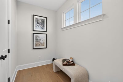 Small room with vaulted ceiling, two framed artworks, upholstered bench, and natural light from windows