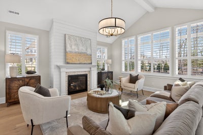 Living room with vaulted ceiling, white shiplap fireplace, and plantation shutters