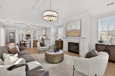 Open concept living room with white shiplap fireplace and view into kitchen with island