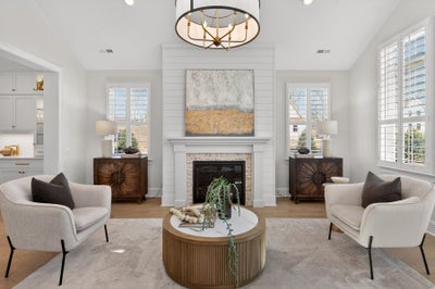 Living room with white shiplap fireplace, vaulted ceiling, and symmetrical seating arrangement