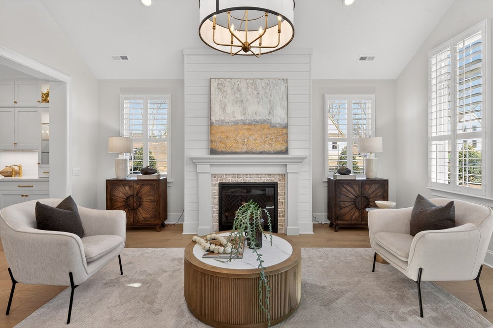 Living room with white shiplap fireplace, vaulted ceiling, and symmetrical seating arrangement