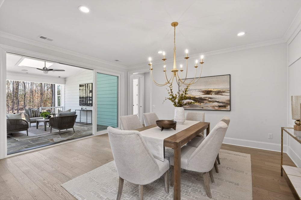 Dining room with wood table, upholstered chairs, gold chandelier, and patio access