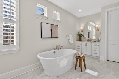 Modern bathroom with freestanding soaking tub, white vanity, and plantation shutters