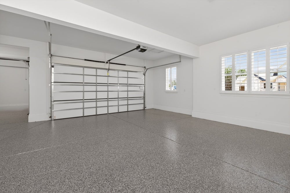 Two-car garage with white walls, speckled epoxy floor, and glass panel door