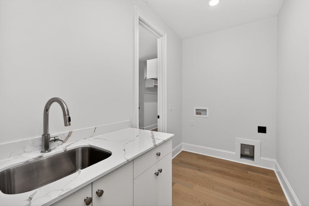 Laundry room with white cabinets, marble countertop, and stainless steel sink