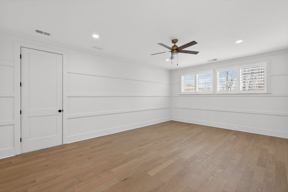 Empty room with white shiplap walls, light hardwood floors, and ceiling fan