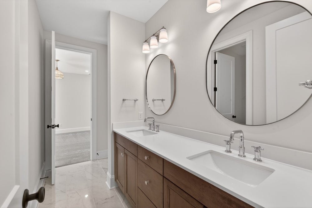 Modern bathroom with double vanity, round mirrors, and wood cabinets