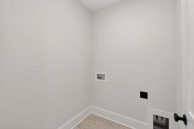 Empty laundry room with white walls, tile floor, and washer-dryer hookups