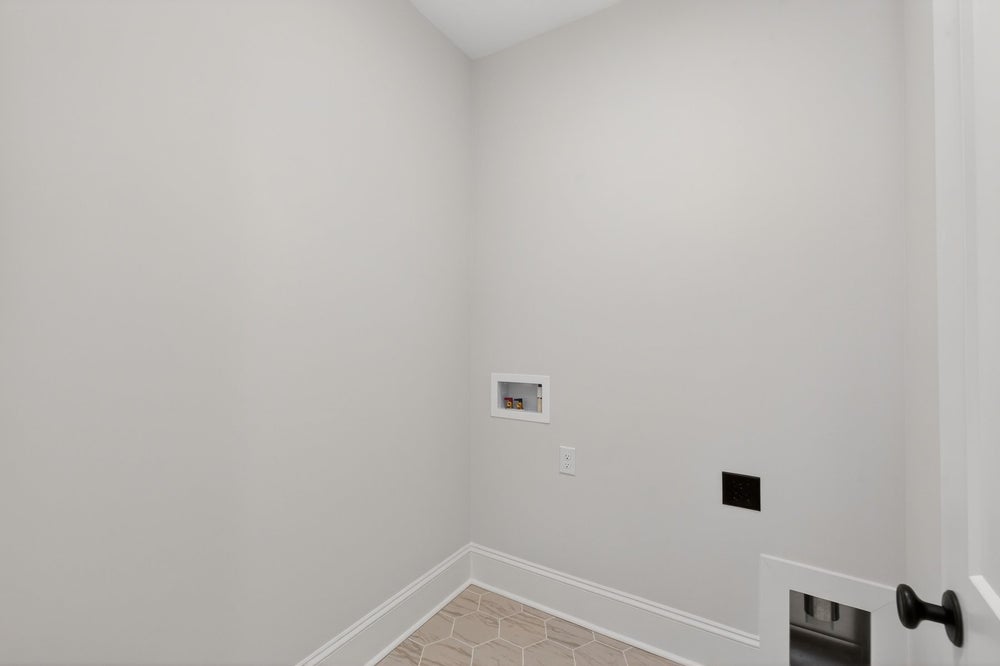 Empty laundry room with white walls, tile floor, and washer-dryer hookups