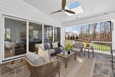 Covered porch with ceiling fan, stone flooring, outdoor furniture, and sliding glass doors overlooking backyard