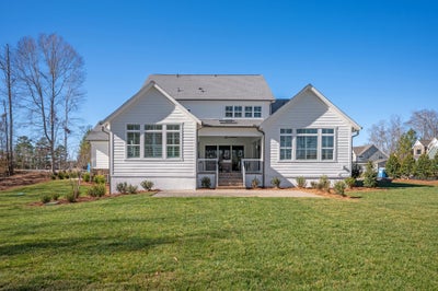 Single-story white craftsman home with covered front porch and landscaped yard