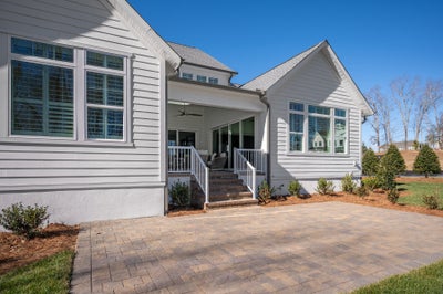 White siding home with covered porch, brick stairs, and paver patio