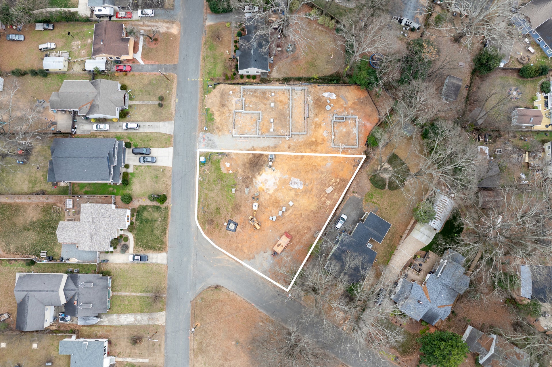 Aerial view of residential construction site with foundation and framing in progress