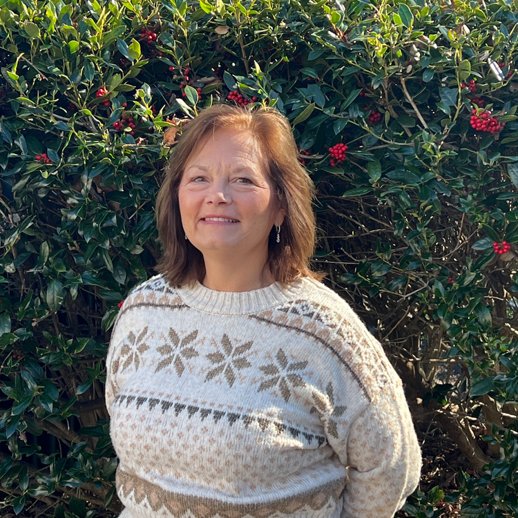 Woman in patterned sweater standing in front of green shrubs with red berries