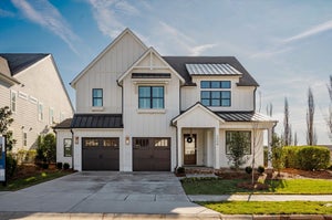 Two-story modern farmhouse with white board-and-batten siding, metal roof accents, and two-car garage