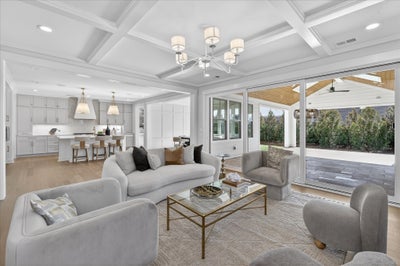 Open-concept living room with coffered ceiling, gray furniture, and sliding doors to covered patio
