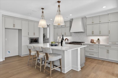 White kitchen with center island, gray cabinets, marble backsplash, and pendant lighting