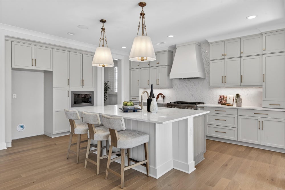 White kitchen with center island, gray cabinets, marble backsplash, and pendant lighting