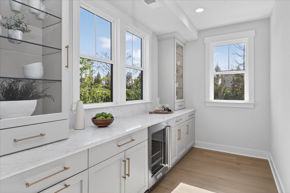 Butler's pantry with white cabinets, marble countertops, and built-in wine fridge
