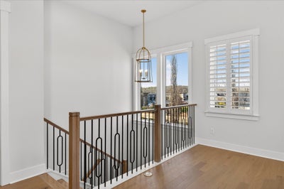 Upper floor landing with decorative metal stair railing and pendant light fixture