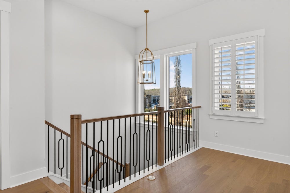 Upper floor landing with decorative metal stair railing and pendant light fixture