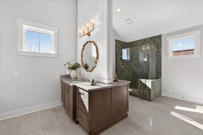 Modern bathroom with wood vanity, round mirror, and glass-enclosed shower with green tile