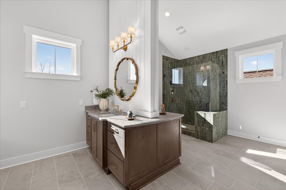 Modern bathroom with wood vanity, round mirror, and glass-enclosed shower with green tile