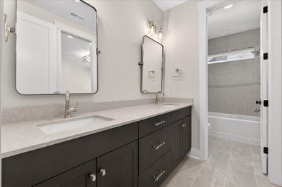 Bathroom with double vanity, dark gray cabinets, white countertops, and tub-shower combo