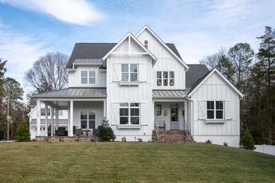 White farmhouse-style home with board and batten siding, front porch, and brick steps