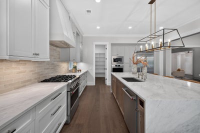Large kitchen with gray cabinets, marble island, gas range, and pendant lighting over dark hardwood floors
