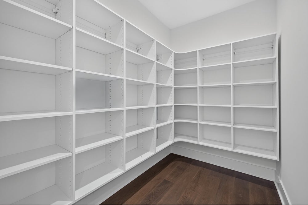 Walk-in pantry or closet with floor-to-ceiling white built-in shelving and dark hardwood floors