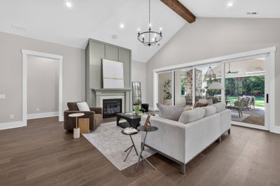 Living room with vaulted ceiling, wood beam, fireplace, and sliding glass doors to outdoor patio