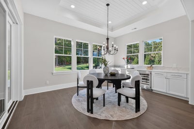 Dining room with round dark wood table, chandelier, hardwood floors, and built-in wet bar with white cabinets