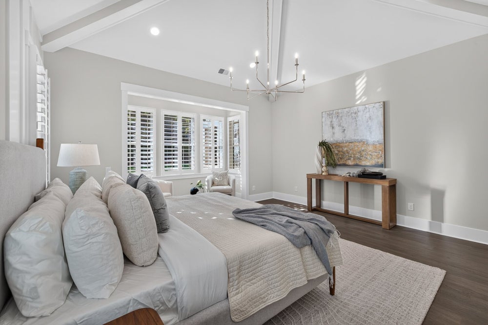 Master bedroom with vaulted beamed ceiling, hardwood floors, and plantation shutters