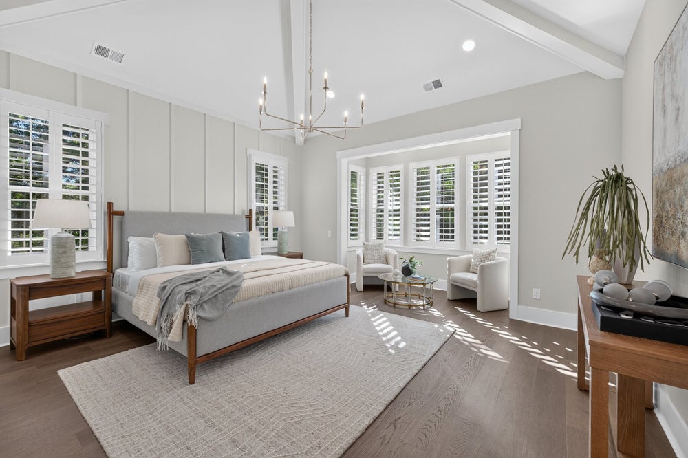 Master bedroom with vaulted ceiling, chandelier, plantation shutters, and hardwood floors