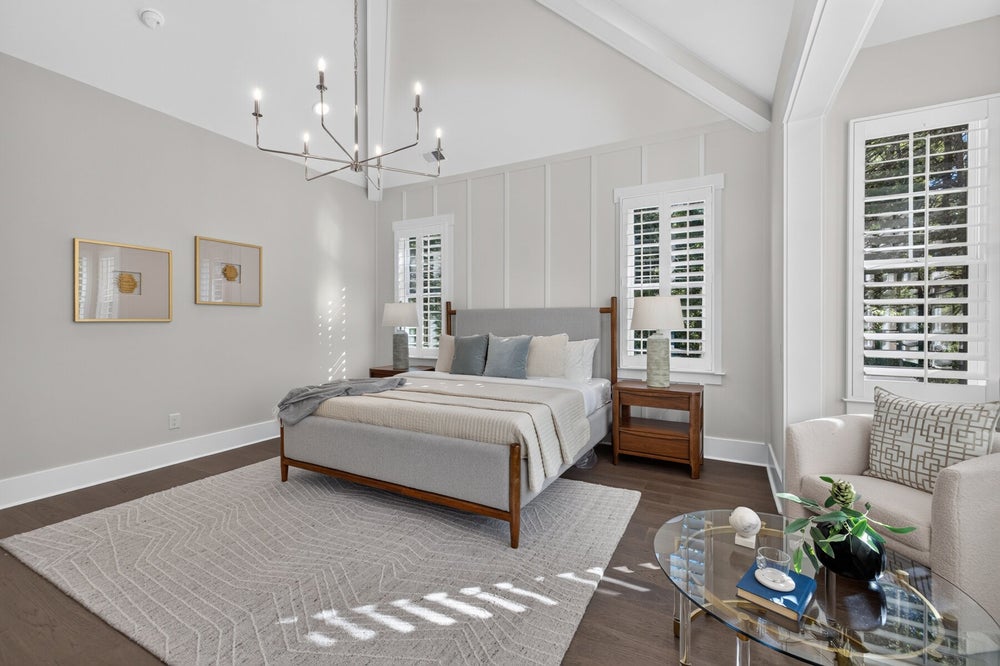 Master bedroom with vaulted beamed ceiling, chandelier, hardwood floors, and plantation shutters