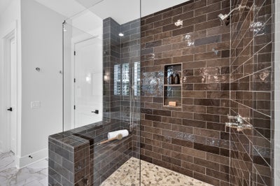 Walk-in shower with dark brown subway tiles, glass enclosure, built-in niche, and tiled bench seat