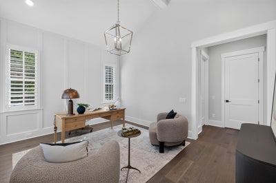 Home office with vaulted ceiling, wood desk, pendant light, and hardwood floors