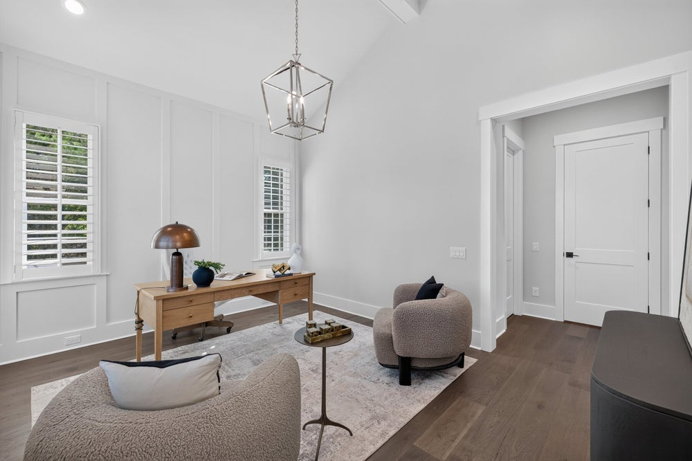 Home office with vaulted ceiling, wood desk, pendant light, and hardwood floors
