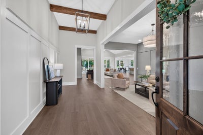 Bright home entryway with wood beam ceiling, hardwood floors, and open view to living areas