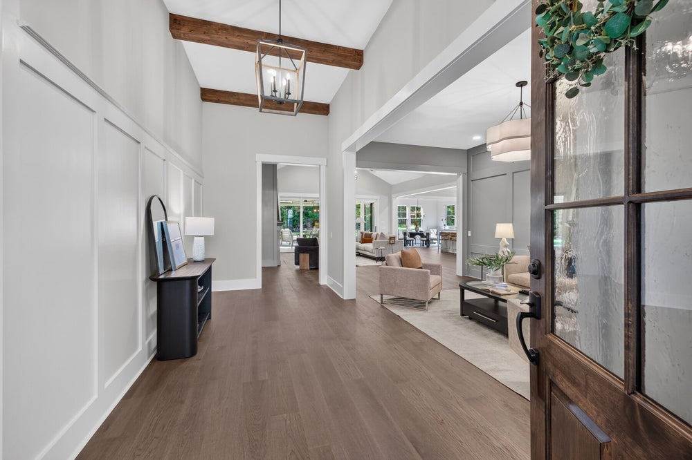 Bright home entryway with wood beam ceiling, hardwood floors, and open view to living areas