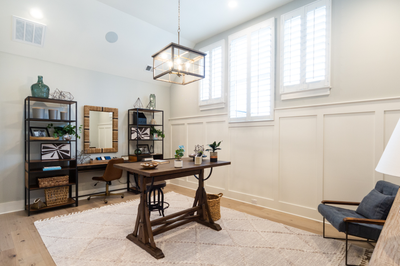 Home office with wooden desk, vaulted ceiling, white wainscoting, and large windows